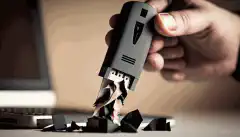 Imagen de una persona sosteniendo una memoria USB con una trituradora de fondo